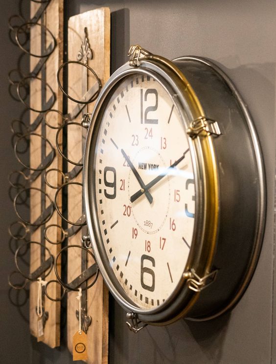 modern brass clock on wall next to wine rack