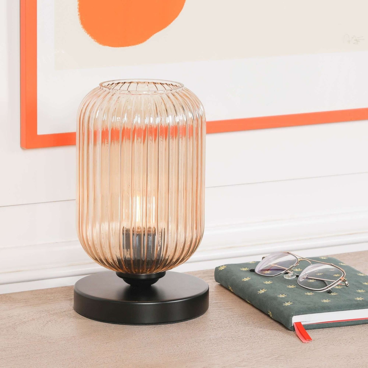 Industrial black table lamp with smoked glass fluted shade and black base on a wooden table.