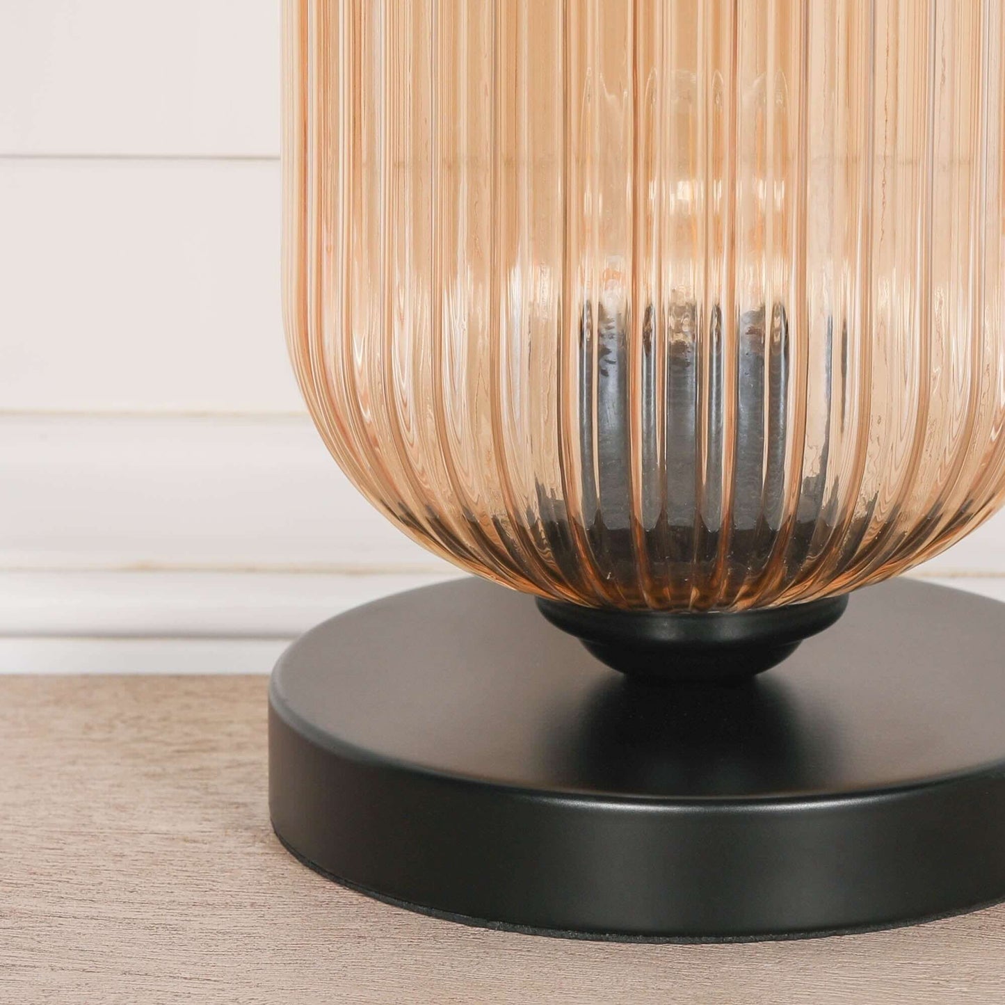 Close-up of an industrial style black table lamp base with a smoked glass fluted shade, showcasing textured glass and sleek design.