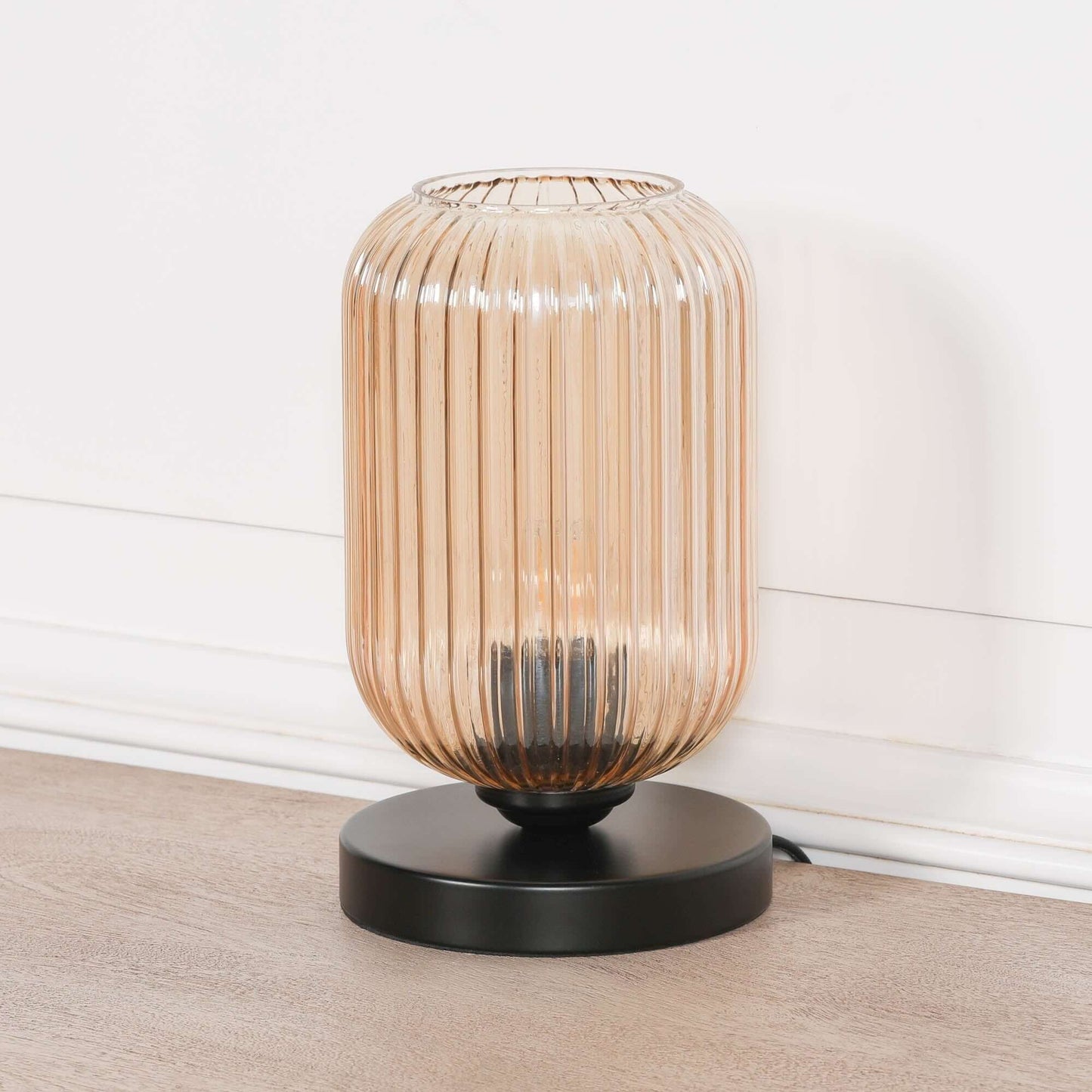 Industrial style black table lamp with smoked glass fluted shade, offering ambient lighting for modern decor.