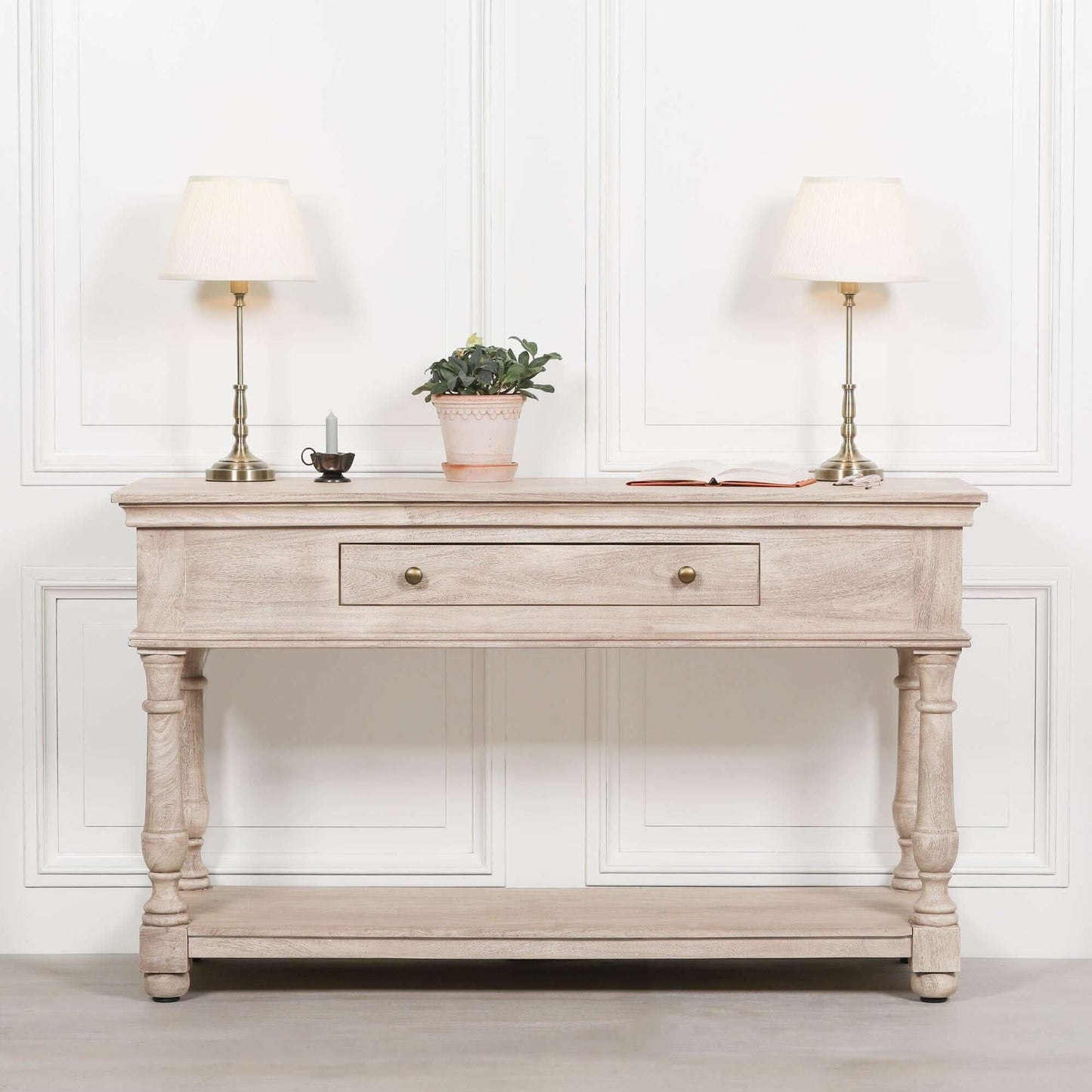 Elegant wooden console table with two brass lamps and a potted plant, perfect for home decor.