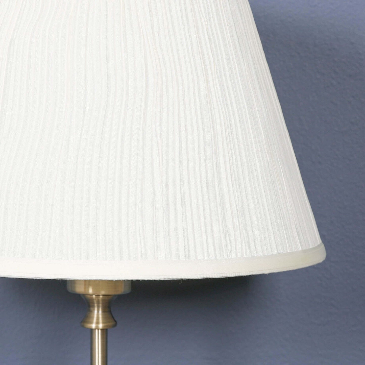 Cream pleated lamp shade with satin brass base, enhancing elegance and warmth in home decor.