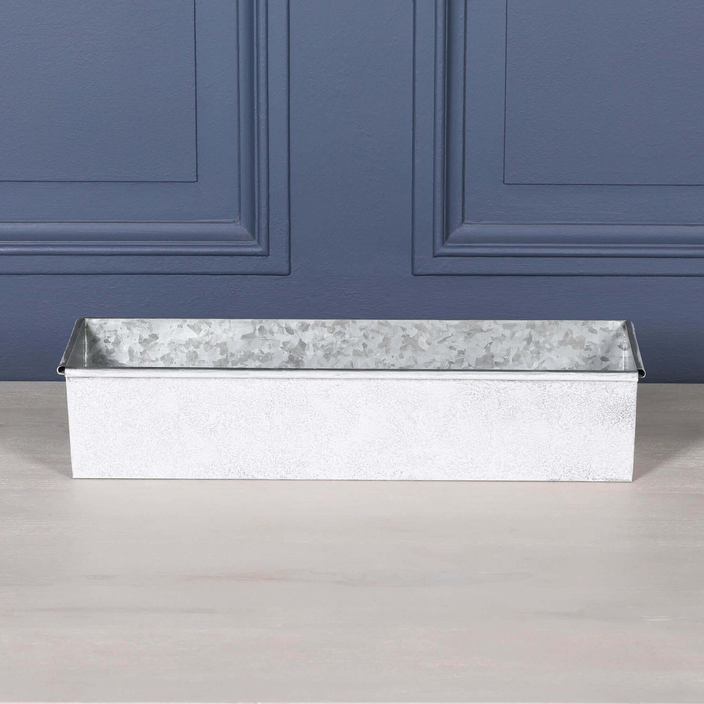 White Wash Metal Window Box Planter on a table, featuring a rustic design with a rolled top edge.