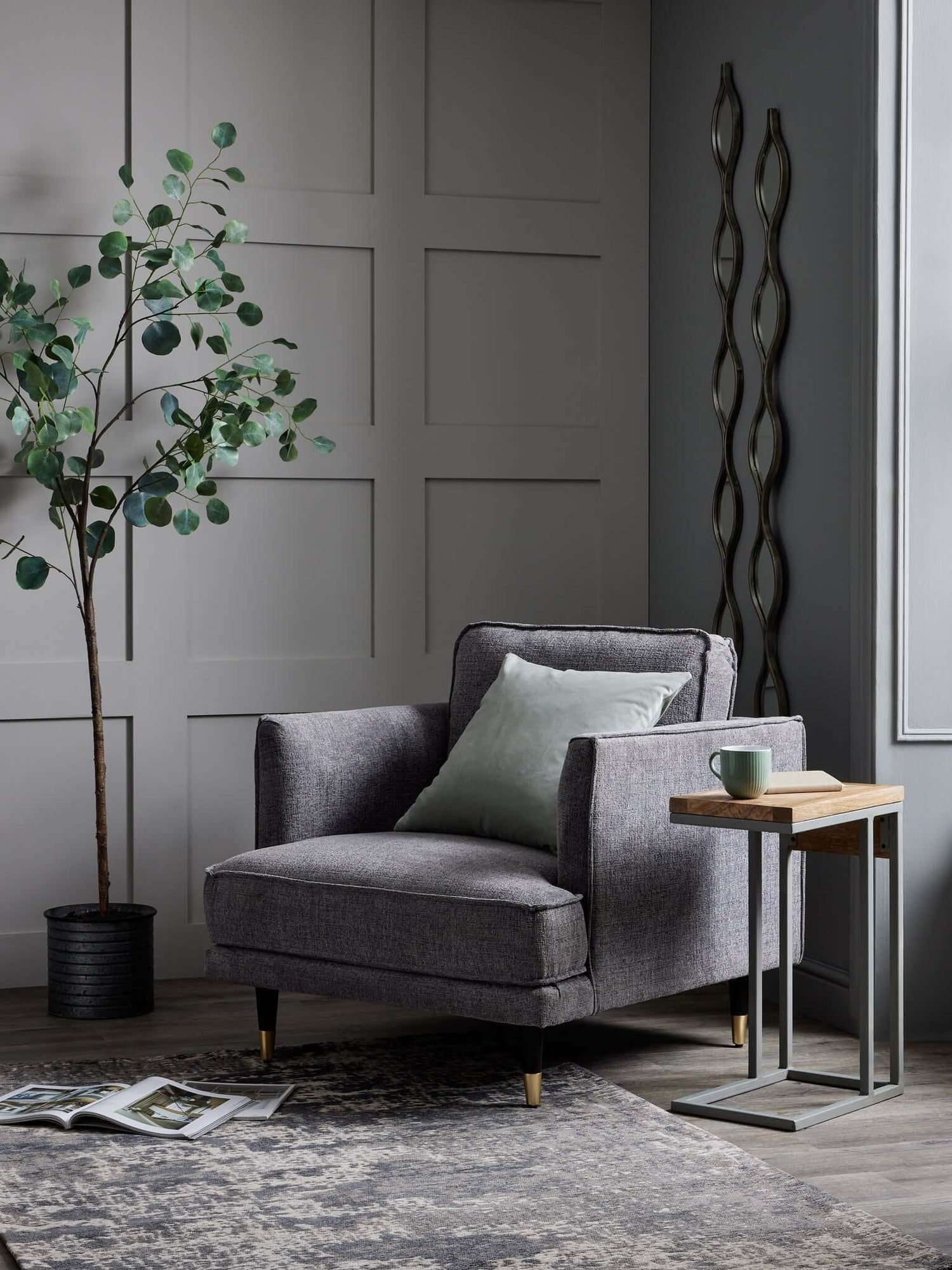 Grey accent chair next to olive plant