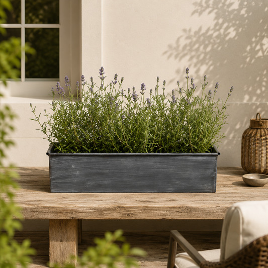 Decorative planter with lavender on a wooden table outdoors.