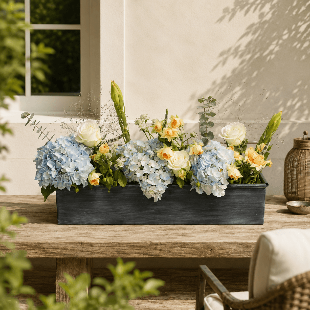 Floral arrangement in an iron planter on a wooden table outdoors.