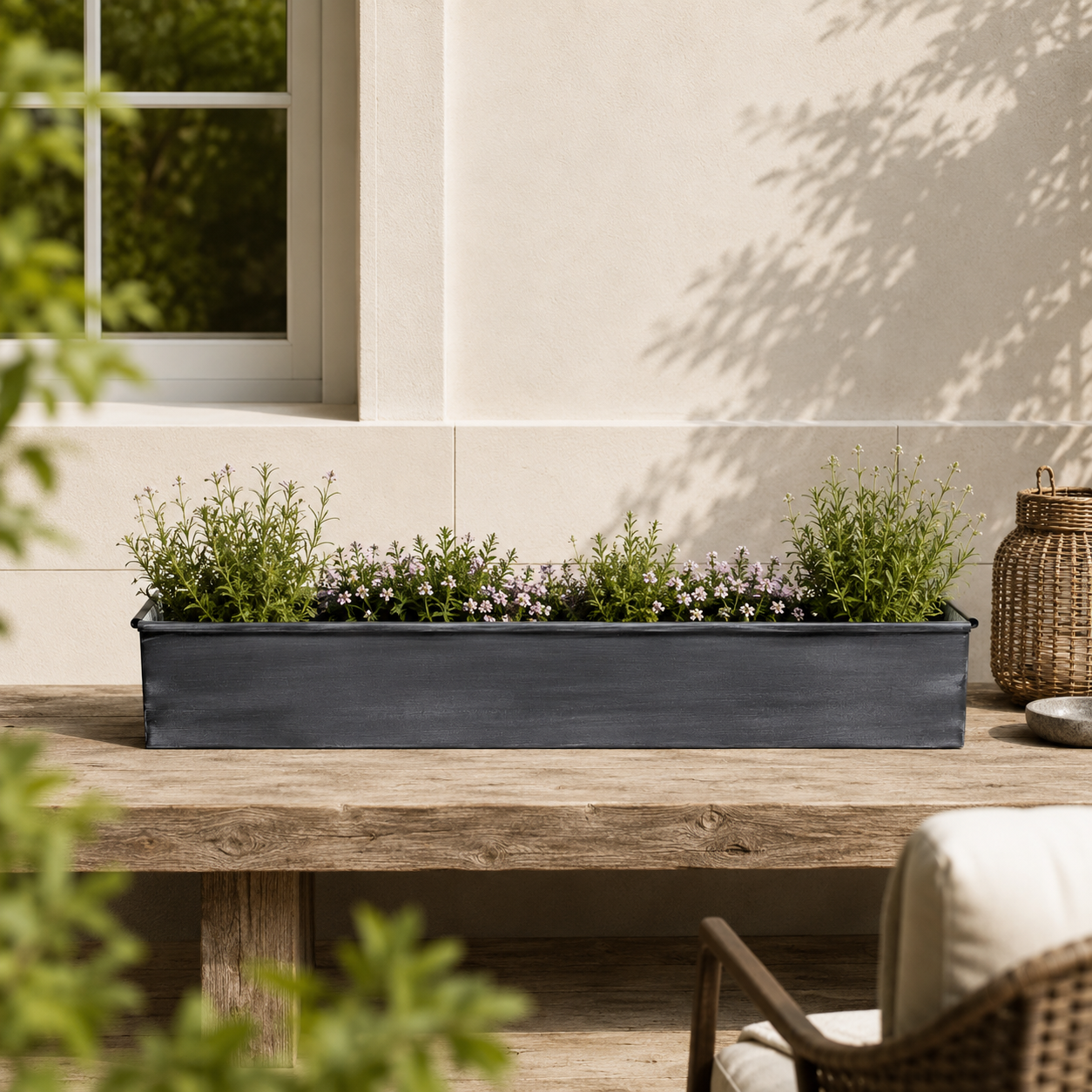 Iron rectangular planter with green plants on a wooden table outdoors.
