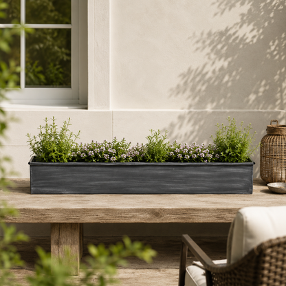Decorative planter with greenery on a wooden table outdoors.