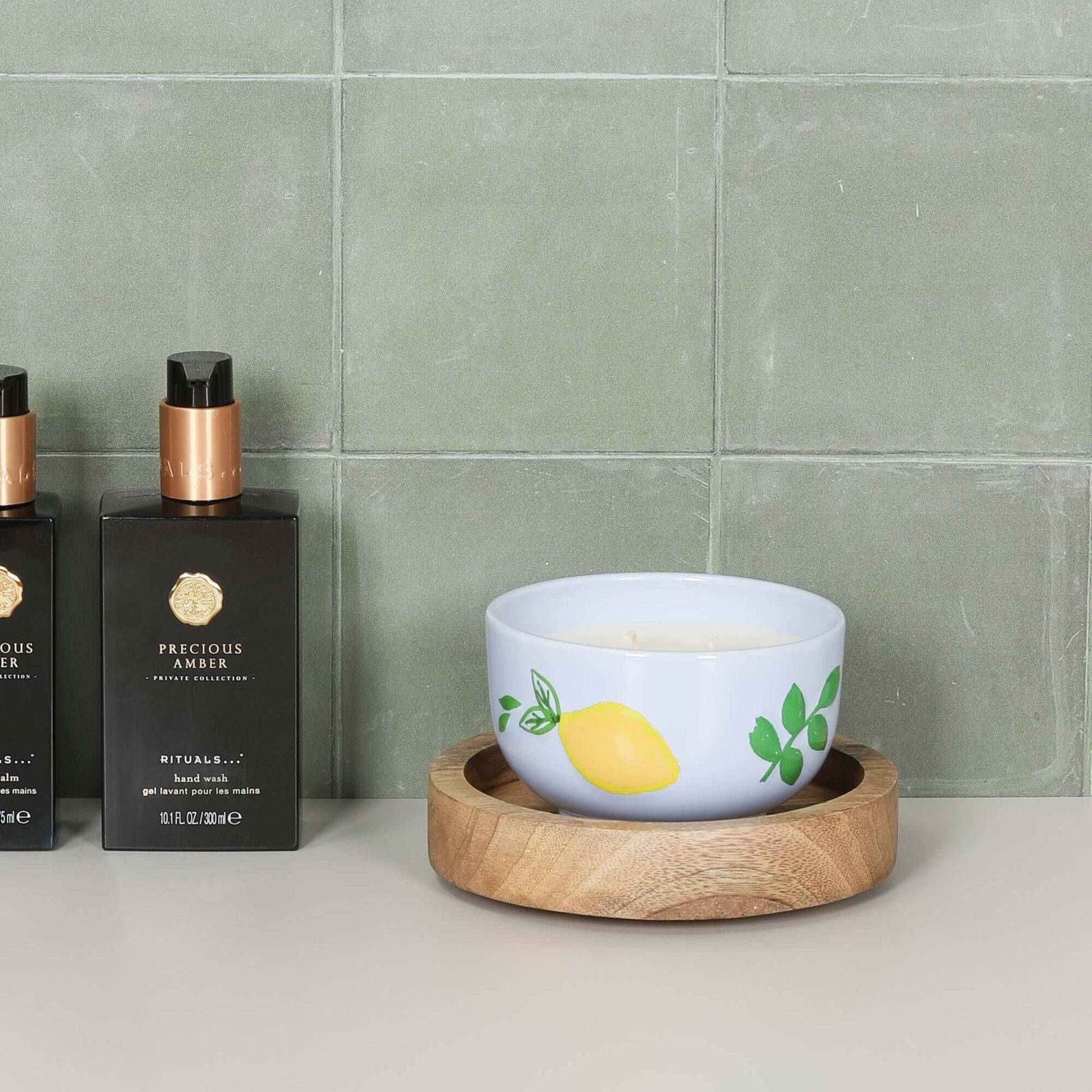 Round 15cm Wooden Tray with a colorful candle bowl and stylish bottles on a tiled countertop.