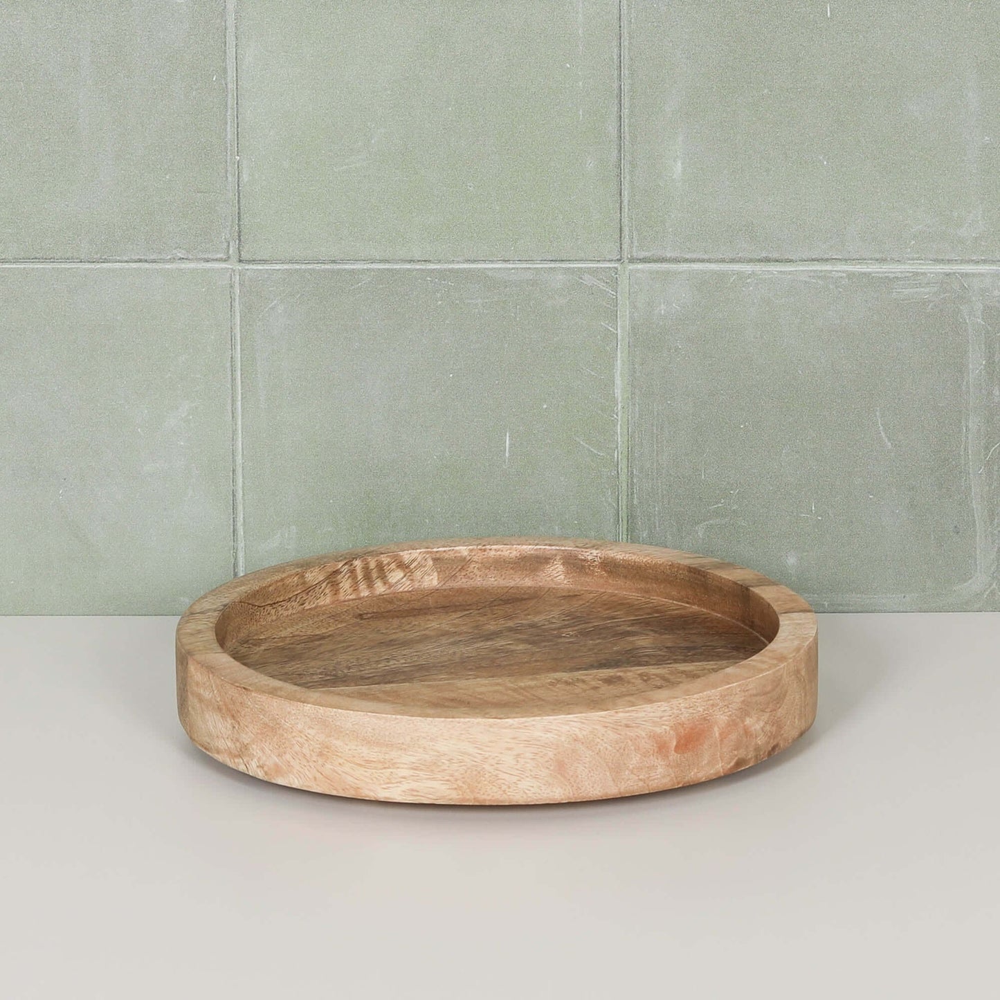 Round 20cm Wooden Tray displayed on a light green tiled surface, showcasing its natural mango wood design.