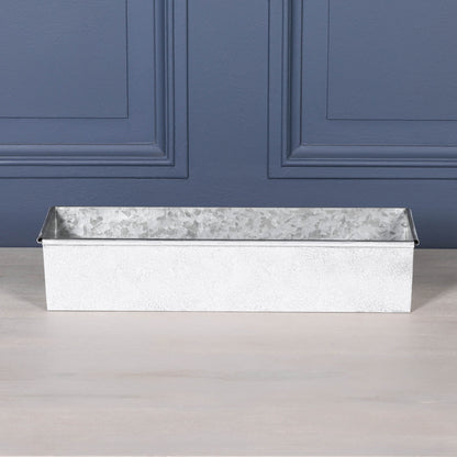 White Wash Metal Window Box Planter on a table, featuring a rustic design with a rolled top edge.