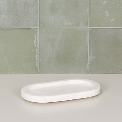 White Marble Long Oval 20cm Tray displayed on a neutral surface against a green tiled background.