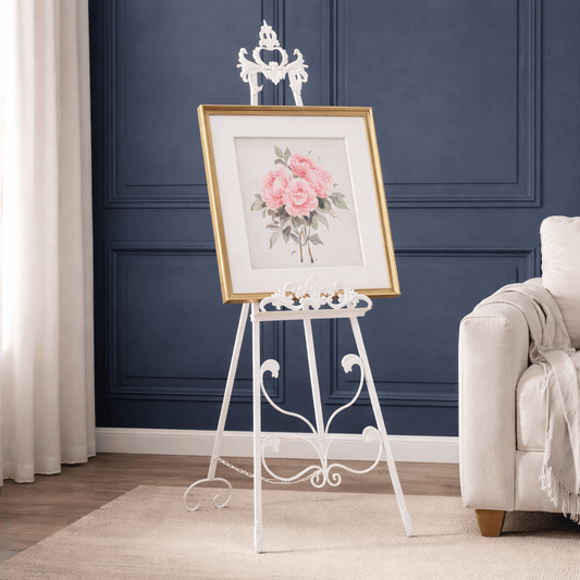Framed floral print on a decorative stand against a blue wall with a sofa.